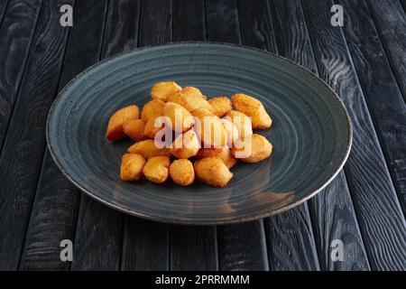 Portion gebratener Kartoffelbällchen auf einem Holztisch Stockfoto