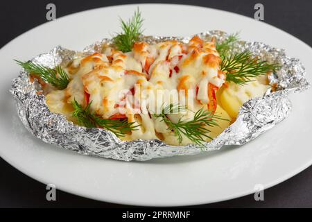 Blick aus nächster Nähe auf gebratenen Seefisch und Kartoffeln mit Paprika und Käse Stockfoto