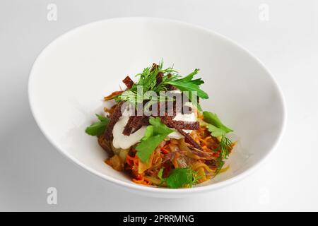 Tiefer Teller mit Salat mit Bohnen, Kohl und eingelegter Gurke Stockfoto