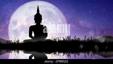 Silhouette von Buddha, der bei Nacht Vollmondlicht vermittelt. Tag von Magha Puja, Asanha Puja und Visakha Puja. Buddhistisches Feiertagskonzept. Stockfoto