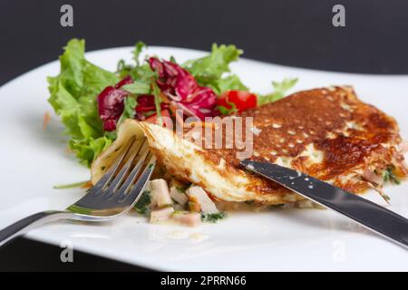 Schneiden mit Messer Omelett mit Schinken und Gemüse Stockfoto