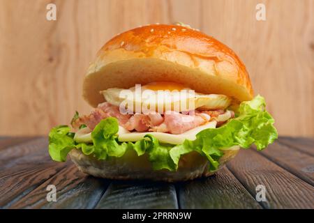 Leckerer Eierburger mit Mozzarella, Salat und gebratenem Speck Stockfoto