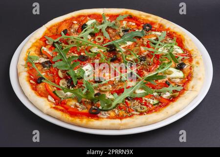 Schlanke Pizza Margherita mit Käse, Rucola, Tomatensauce auf einem weißen Teller. Stockfoto