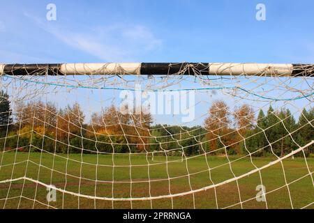 Altes Fußballtor vor dem Hintergrund des Fußballfeldes und des Herbstwaldes. Stockfoto