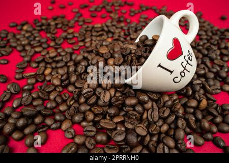 Eine Tasse gefüllt mit Kaffeebohnen auf einem roten Hintergrund mit der Aufschrift i love Coffee Stockfoto