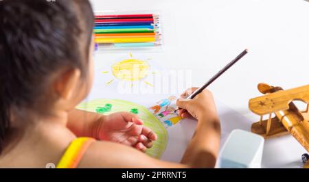 Ein kleines Mädchen, eine farbenfrohe Zeichnerfamilie, die auf dem Planeten Erde auf Papier Händchen hält Stockfoto