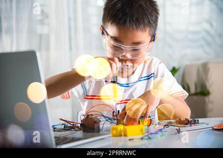 Asiatischer Junge, der zu Hause das Heimprojekt des Arduino-Roboters zusammenführt Stockfoto