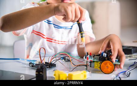 Asiatischer Junge, der zu Hause das Heimprojekt des Arduino-Roboters zusammenführt Stockfoto