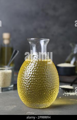 Frisches Sesamöl in Glasflasche auf grauem Tisch Stockfoto