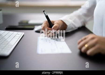 Frau Unterschreibt Bankscheck Stockfoto