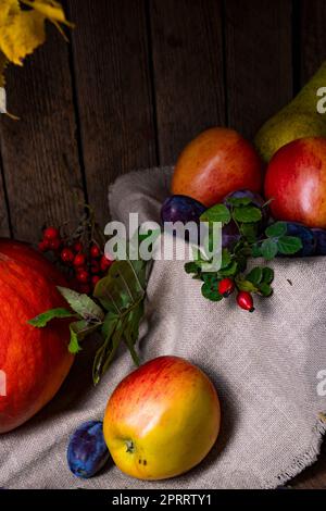Verschiedene Früchte in einer Holzkiste mit Herbstblättern Stockfoto