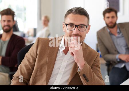 Anführer, dem Ihr vertrauen könnt. Ein positiver reifer Designer lächelt in einem gemeinsamen Büro an der Kamera. Stockfoto