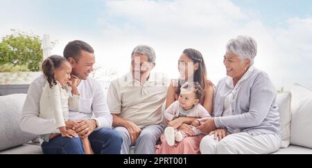 Glückliche Familie mit Kindern und Großeltern, die sich unterhalten, Kommunikation und Konversation auf der Couch im Haus der Familie. Große Familie von älteren Rentnern, Liebe und jungen Kindern lächeln zusammen Stockfoto