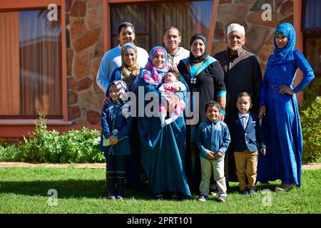 Familie zuerst. Porträt einer glücklichen muslimischen Familie, die vor ihrem Haus zusammensteht. Stockfoto