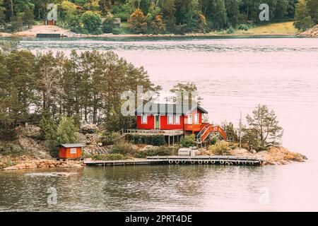 Schweden. Im Sommer Gibt Es Viele Schöne Rote Schwedische Holzhütten An Der Rocky Island Küste. See- Oder Flusslandschaft. Stockfoto