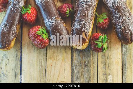 Schokoladen-Profiteroles und frische Erdbeeren auf einem Holztisch Stockfoto