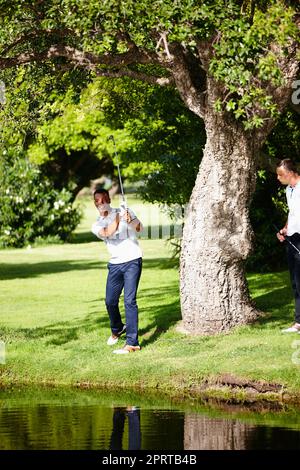 Er mag es nicht rau. Ein junger Mann, der seinen Golfschuss aus dem Rough nimmt. Stockfoto