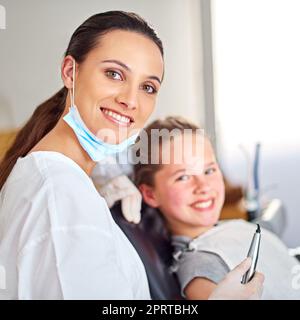 Sie kümmert sich gut um ihre jungen Patienten. Porträt einer attraktiven Zahnärztin und ihres Kinderpatienten. Stockfoto