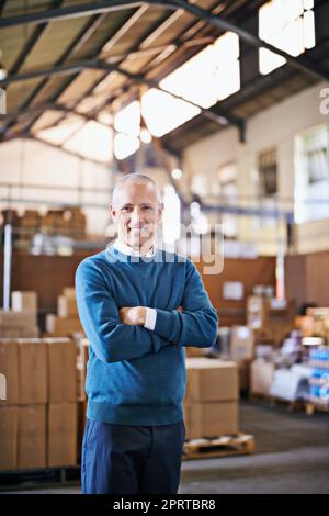 Logistik ist unser Geschäft. Porträt eines reifen Mannes, der in einem Distributionslager steht. Stockfoto