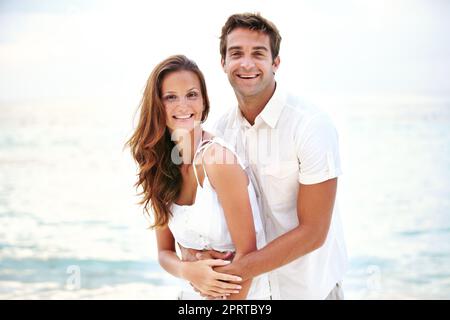 Entspannt und verliebt. Porträt eines wunderschönen jungen Paares, das sich liebevoll am Strand hält. Stockfoto