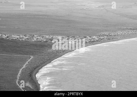 Blick auf Playa de Famara. Blick vom Mirador Rincon de Haria. Super-Zoom-Objektiv. Schwarz und Weiß. Lanzarote. Kanarische Inseln. Spanien. Stockfoto