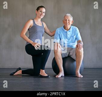 Ich halte meine Patienten jung und sprituhaft. Ein Physiotherapeut, der mit einem älteren Mann zusammenarbeitet. Stockfoto