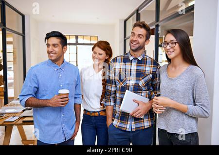 Erfolg folgt harter Arbeit. Vier junge Designer stehen in ihrem modernen Büro. Stockfoto