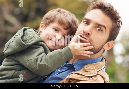 Gesichter machen und Spaß haben. Ein Vater und Sohn genießen einen Tag im Freien. Stockfoto