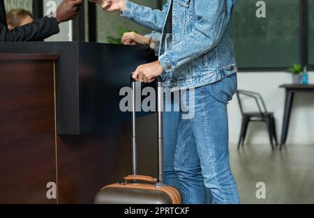 Ein junges Paar an der Hotelrezeption zum Einchecken. Stockfoto