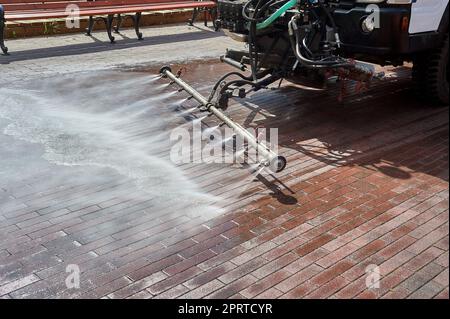 Eine spezielle Maschine wäscht Stadtwege und Straßen mit Wasser Stockfoto