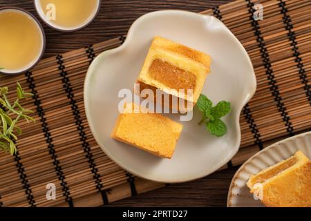 Köstliches taiwanesisches berühmtes Ananaskuchen Gebäck als Dessert auf einem Teller auf einem Holztisch mit heißem Tee. Stockfoto