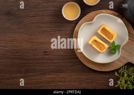 Köstliches taiwanesisches berühmtes Ananaskuchen Gebäck als Dessert auf einem Teller auf einem Holztisch mit heißem Tee. Stockfoto