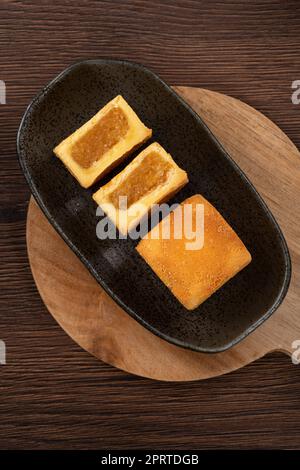 Köstliches taiwanesisches berühmtes Ananaskuchen Gebäck als Dessert auf einem Teller auf einem Holztisch mit heißem Tee. Stockfoto