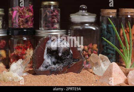 Chakra-Steine mit Aloe Vera und Blumen auf australischem rotem Sand Stockfoto