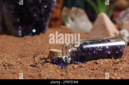 Glas aus lila Steinen auf rotem australischem Sand mit Kristallen im Hintergrund Stockfoto