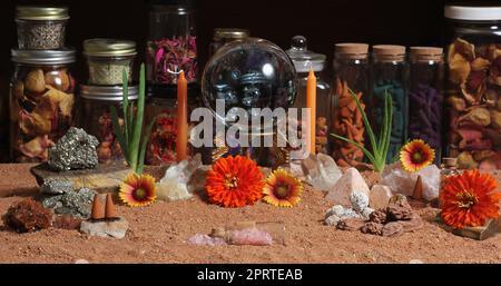 Kristallkugel mit Kerzen und Chakra-Steinen auf australischem rotem Sand Stockfoto
