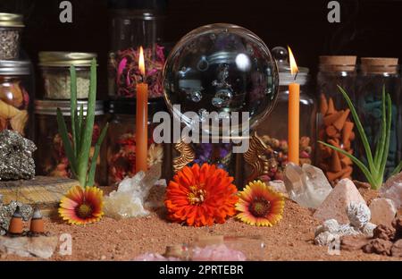 Kristallkugel mit Kerzen und Chakra-Steinen auf australischem rotem Sand Stockfoto