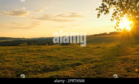 Hügelige Landschaft im saarland. Sonnenuntergang auf einer Wiese mit Blick auf das Tal Stockfoto