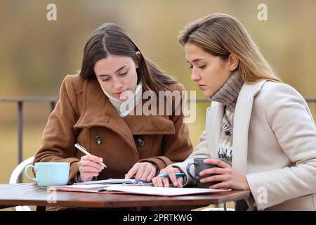 Zwei Schüler, die auf einer Terrasse Notizen lesen Stockfoto