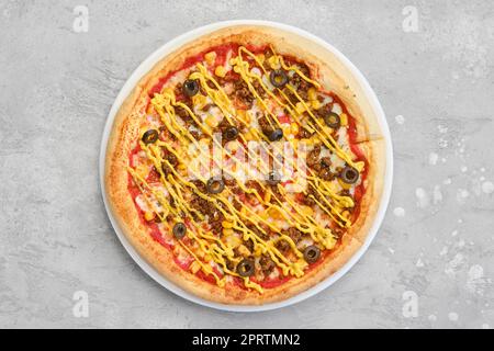 Draufsicht auf kleine Pizza mit Hackfleisch, Zuckermais und Senf Stockfoto