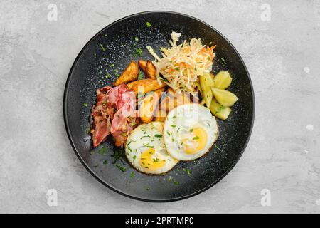 Blick von oben auf Spiegeleier mit Speck und eingelegtem Kohl mit Gurke Stockfoto