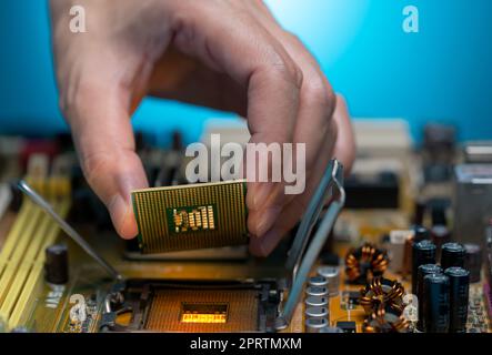 Elektronikingenieur, der Computerchip auf die Buchse legt. Chipsatz auf der elektronischen Leiterplatte der PC-Hauptplatine. CPU-Chip. Elektronische Komponenten. Kom Stockfoto