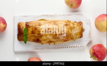 Gebackener Strudel mit Äpfeln auf einem weißen Holzbrett, köstliches Dessert Stockfoto