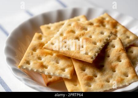 Viele Cracker auf einer Platte, die auf einem weißen Hintergrund mit Platz platziert ist. Nahaufnahme. Stockfoto