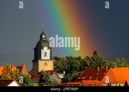 Ein Regenbogen hinter der Kirche von Herleshausen in Hessen Stockfoto