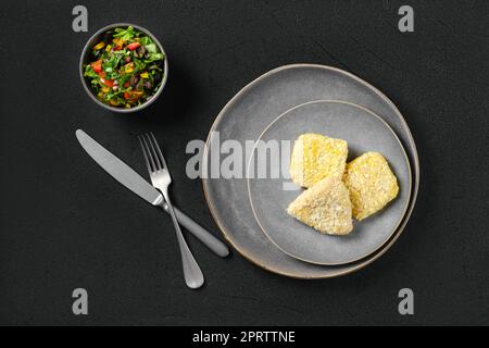 Draufsicht auf halbfertiges Kalmare-Schnitzel bei der Panade Stockfoto