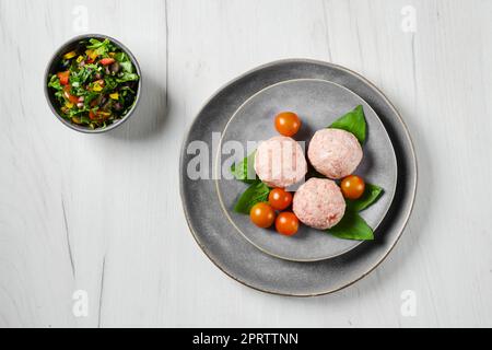 Ansicht von halbfertigen gefrorenen Kalbfleischbällchen auf einem Teller Stockfoto