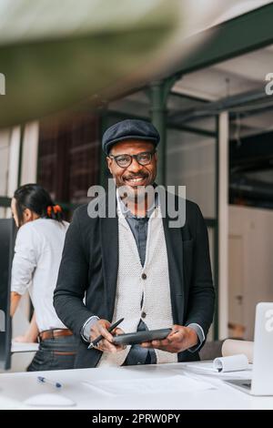 Lächelnder, reifer Geschäftsmann mit Tablet-PC im Büro Stockfoto