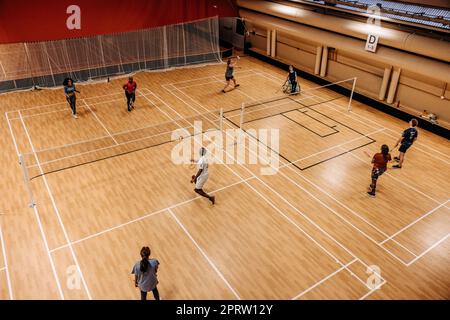 Blick aus der Vogelperspektive auf männliche und weibliche Athleten, die auf dem Sportplatz Badminton spielen Stockfoto