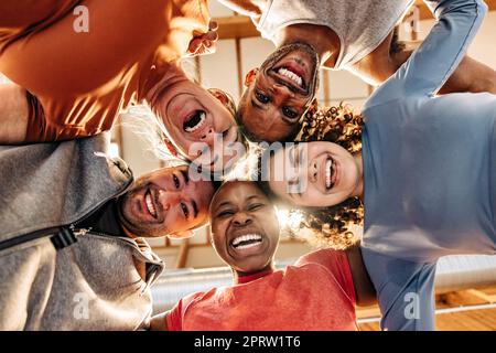 Direkt unter dem Bild von fröhlichen männlichen und weiblichen Athleten, die sich auf dem Sportplatz zusammentun Stockfoto